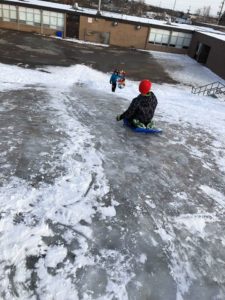 children sliding down sheer ice hill
